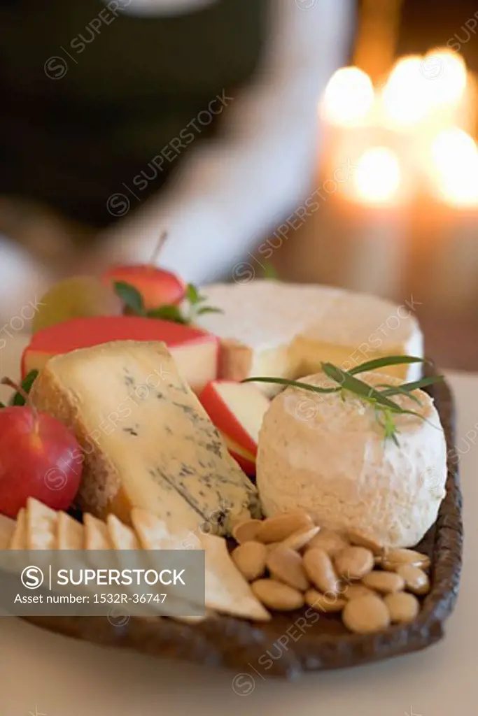 Cheeseboard with fruit and crackers, woman in background