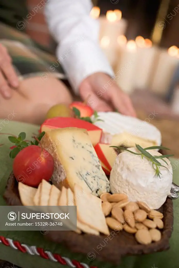 Hands serving cheeseboard with fruit and crackers