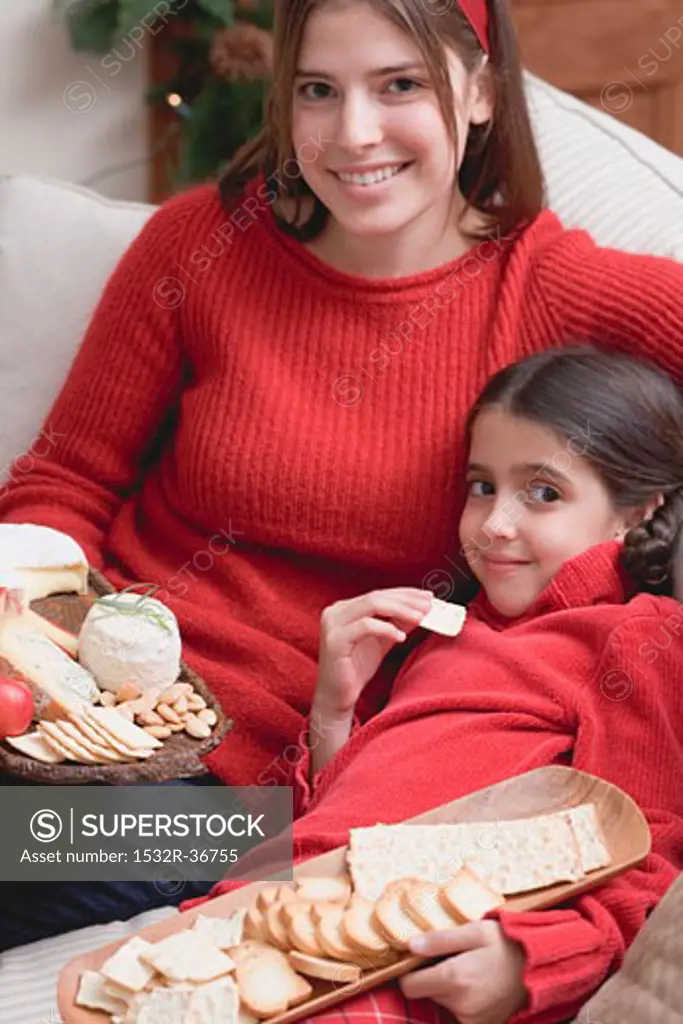 Mother and daughter on sofa with cheeseboard and crackers