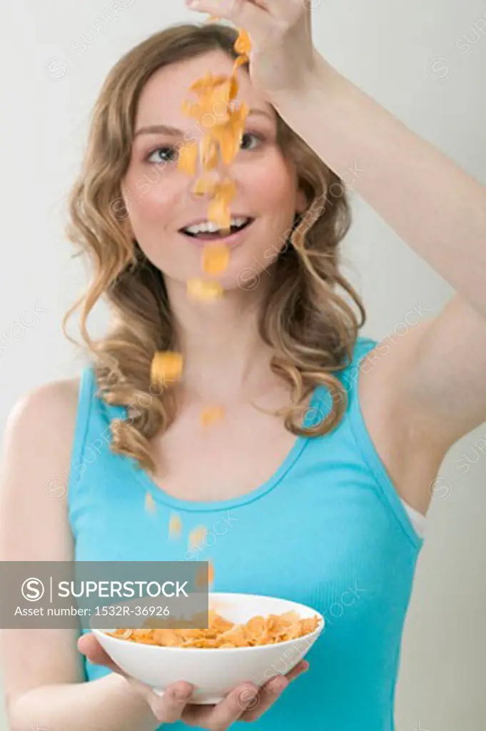 Woman dropping cornflakes into bowl