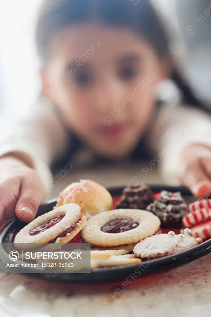 Girl reaching for plate of biscuits