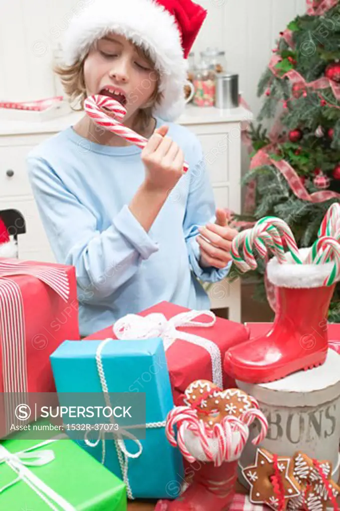 Boy in Father Christmas hat eating candy cane