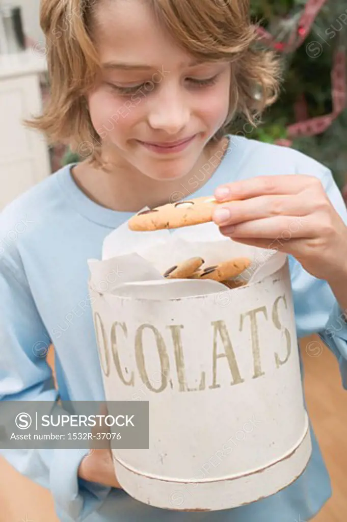 Boy taking chocolate chip cookie out of cookie tin