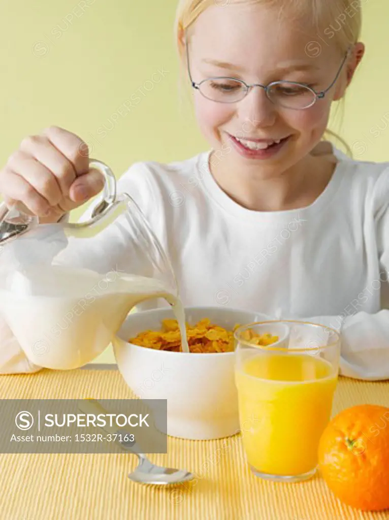 Girl pouring milk over cornflakes