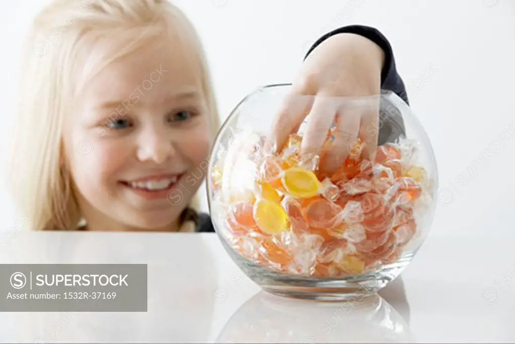Blond girl reaching into a sweet jar