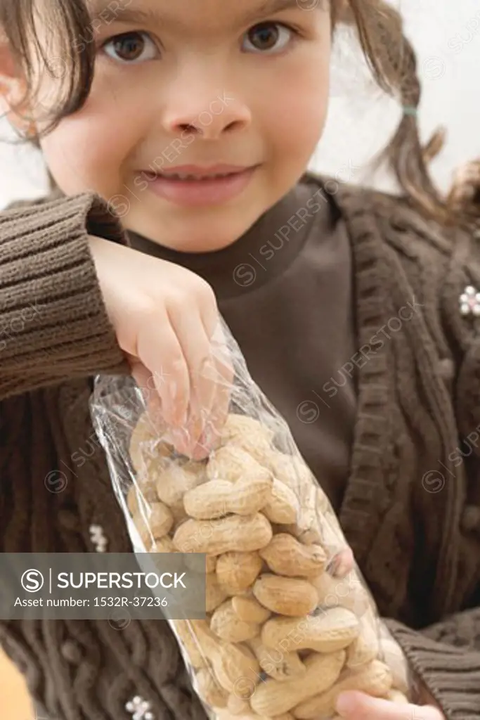 Girl reaching into a bag of peanuts