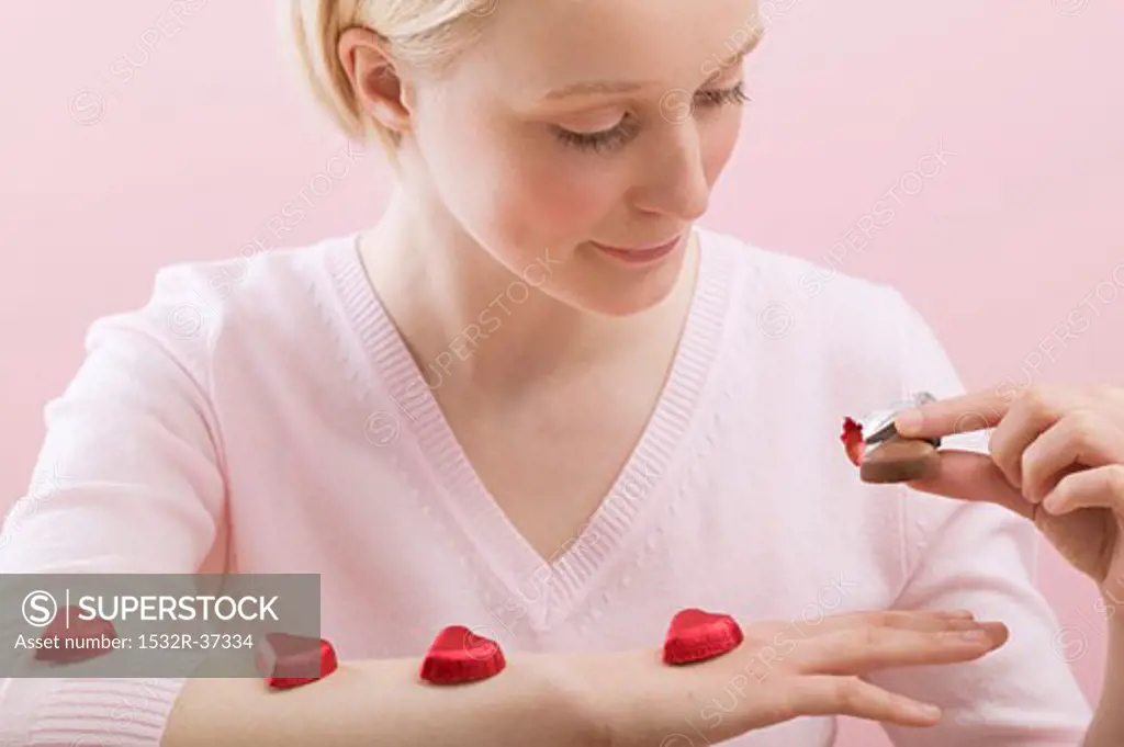 Young woman with red chocolate hearts on her arm