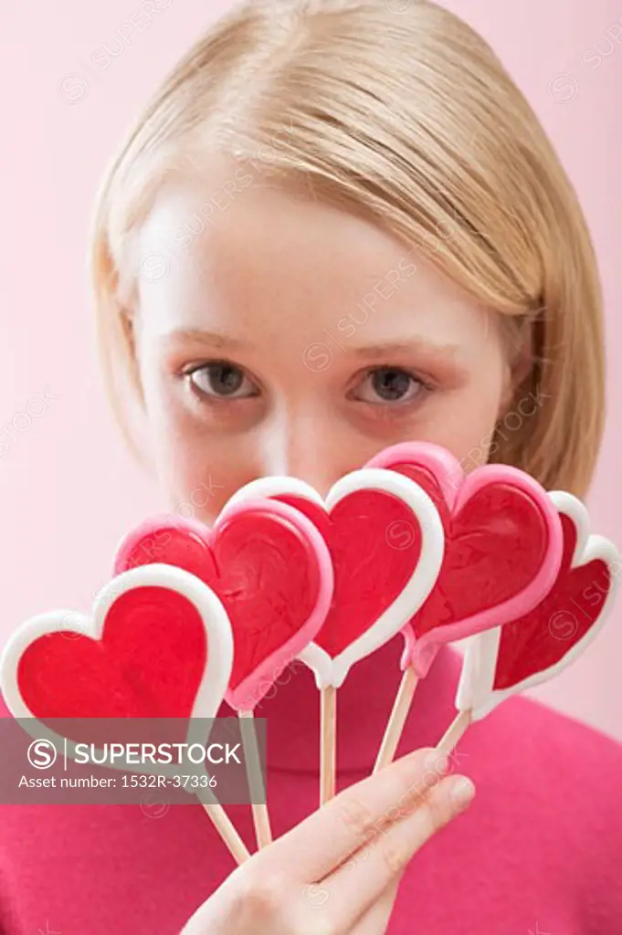 Young woman with several heart-shaped lollipops