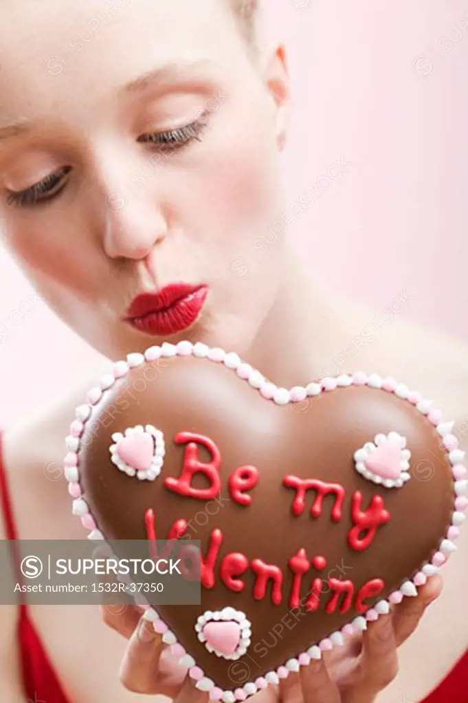 Young woman holding a chocolate heart for Valentine's Day