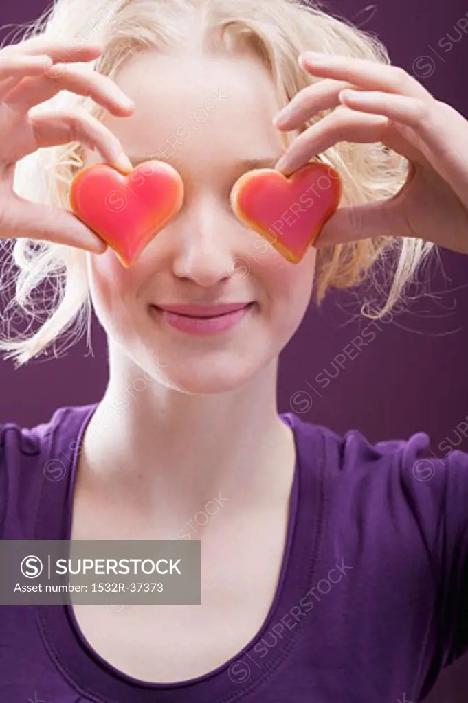 Young woman holding hearts in front of her eyes