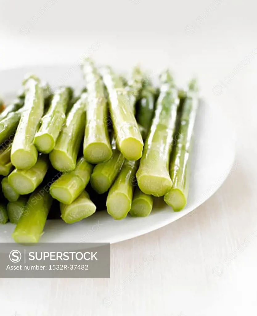 Cooked green asparagus spears on white plate