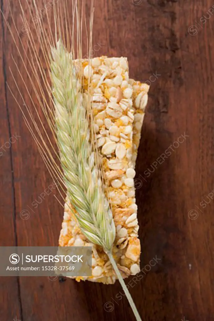 Muesli bars with ear of barley on wooden background