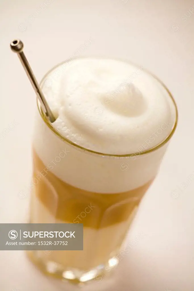 A glass of latte macchiato with coffee spoon