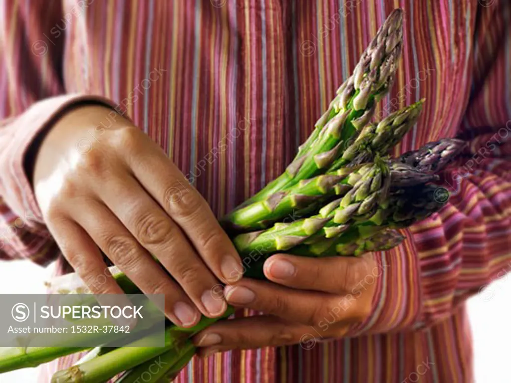 Person holding fresh green asparagus spears