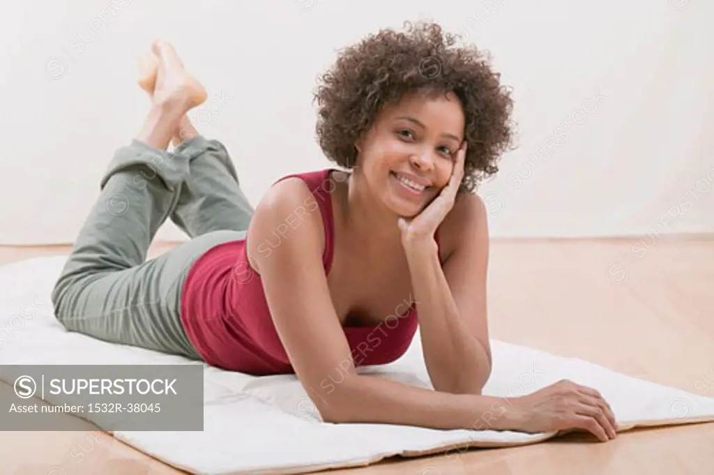 Cheerful young woman lying on a mat (relaxed)