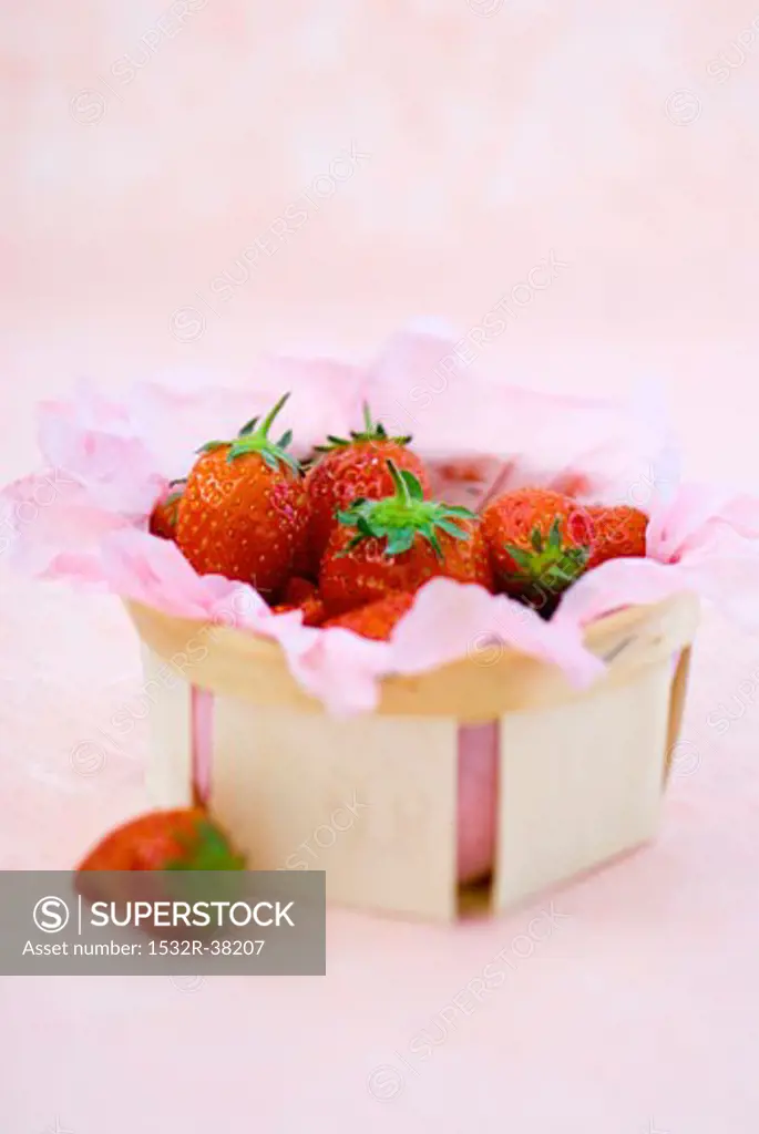 Strawberries in and beside a punnet lined with paper