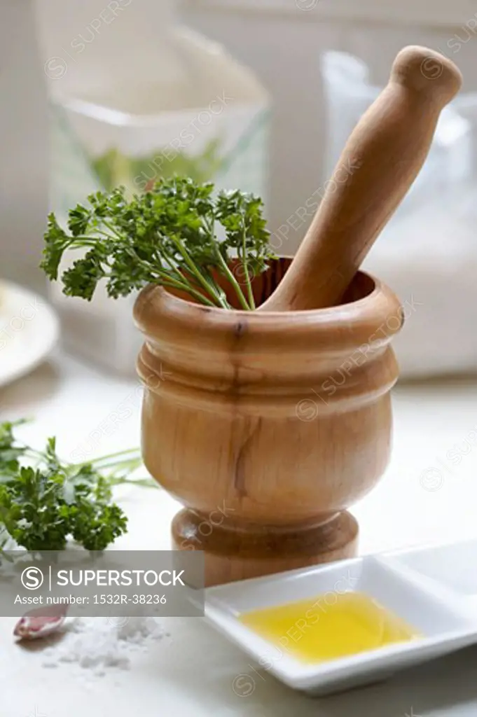 Wooden pestle & mortar with ingredients for parsley pesto