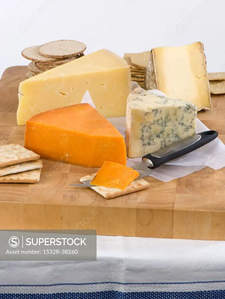 Various cheeses with crackers on a wooden board