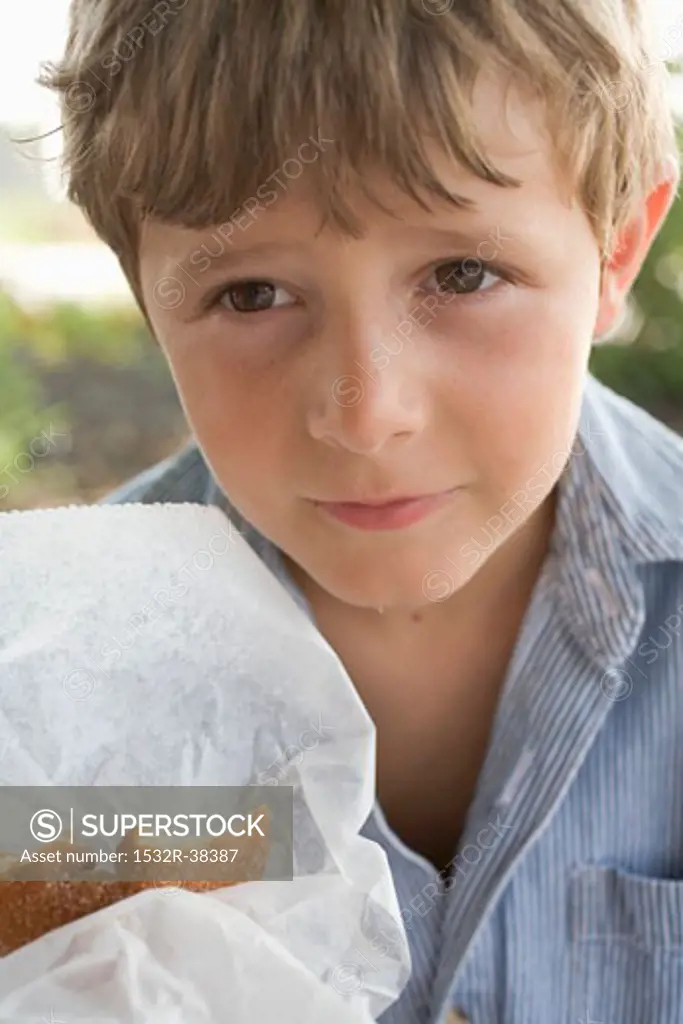 Small boy holding a doughnut in paper