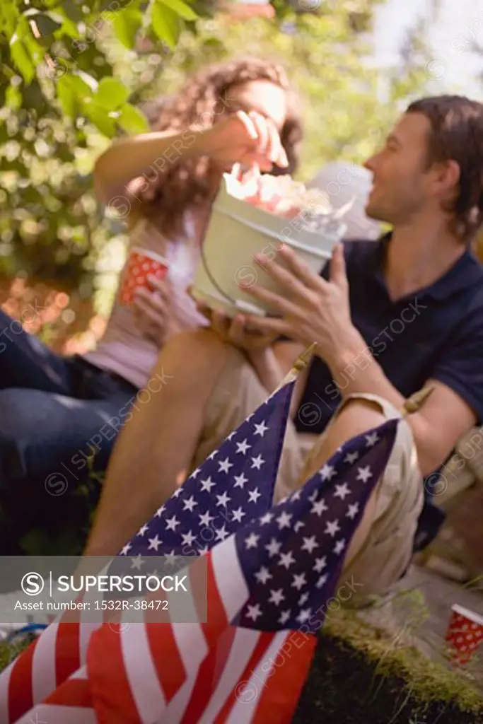 Couple with popcorn in wooden bucket on the 4th of July (USA)