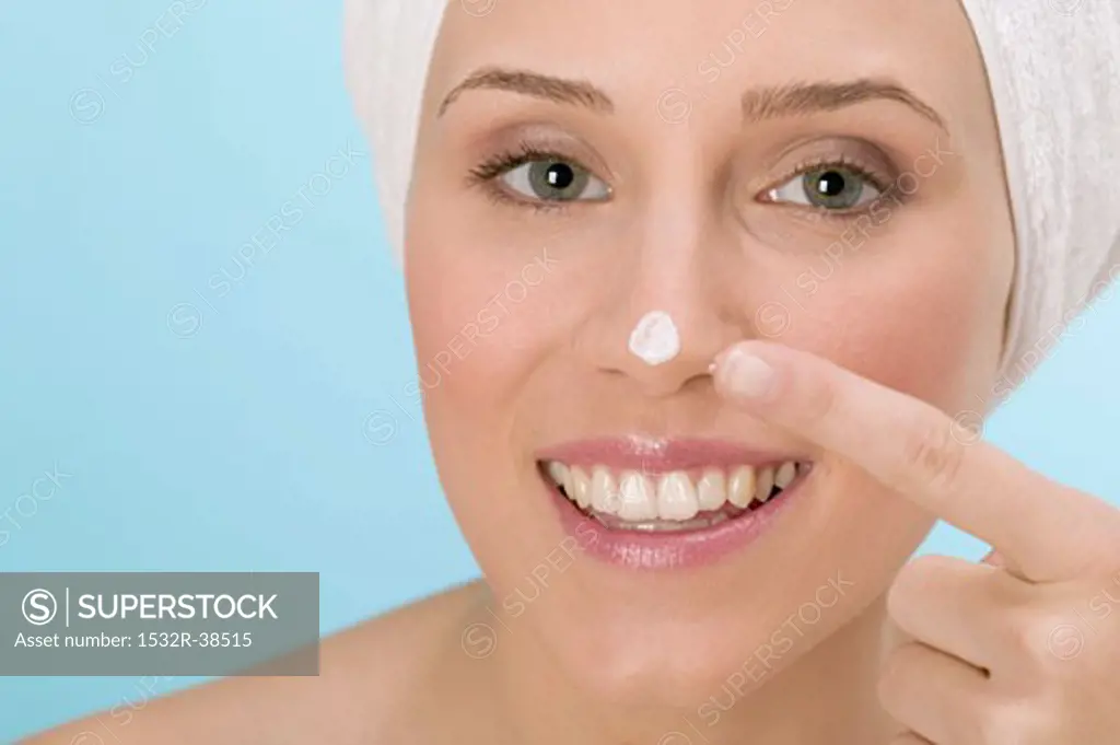 Woman dabbing face cream on her nose