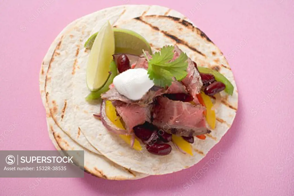 Beef fajita with beans, peppers and sour cream