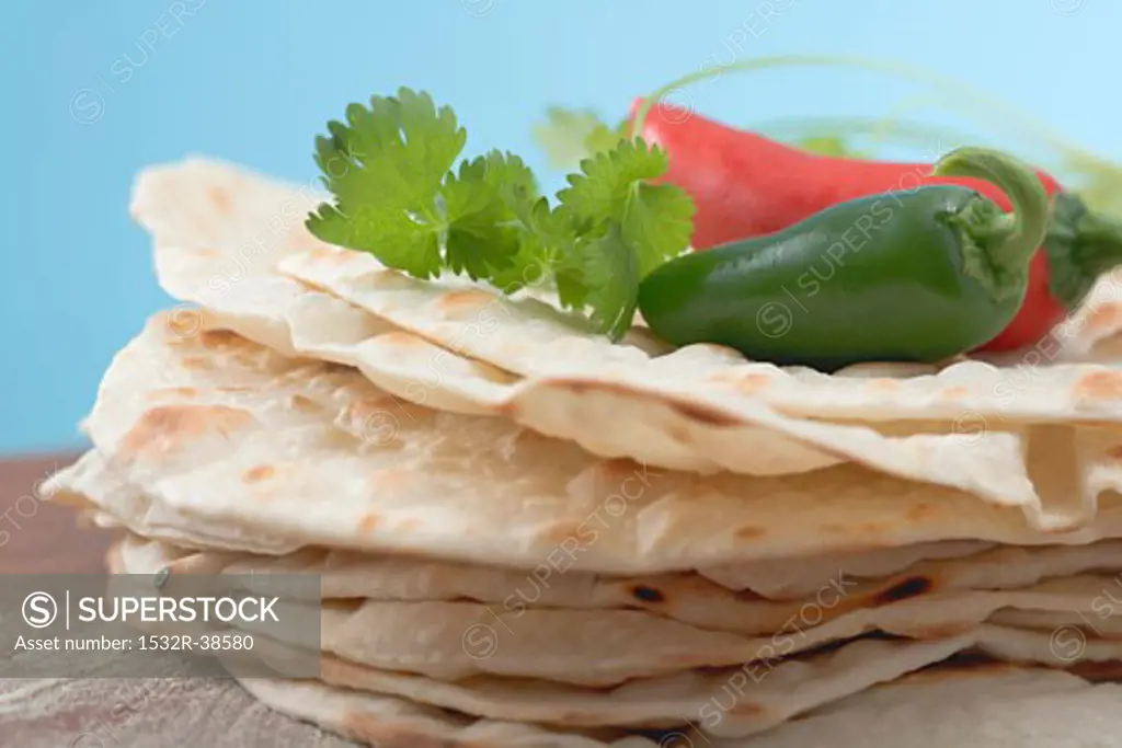 Tortillas, stacked, with fresh coriander and chillies