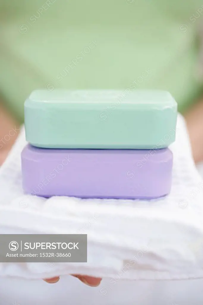 Woman holding two bars of soap on towel