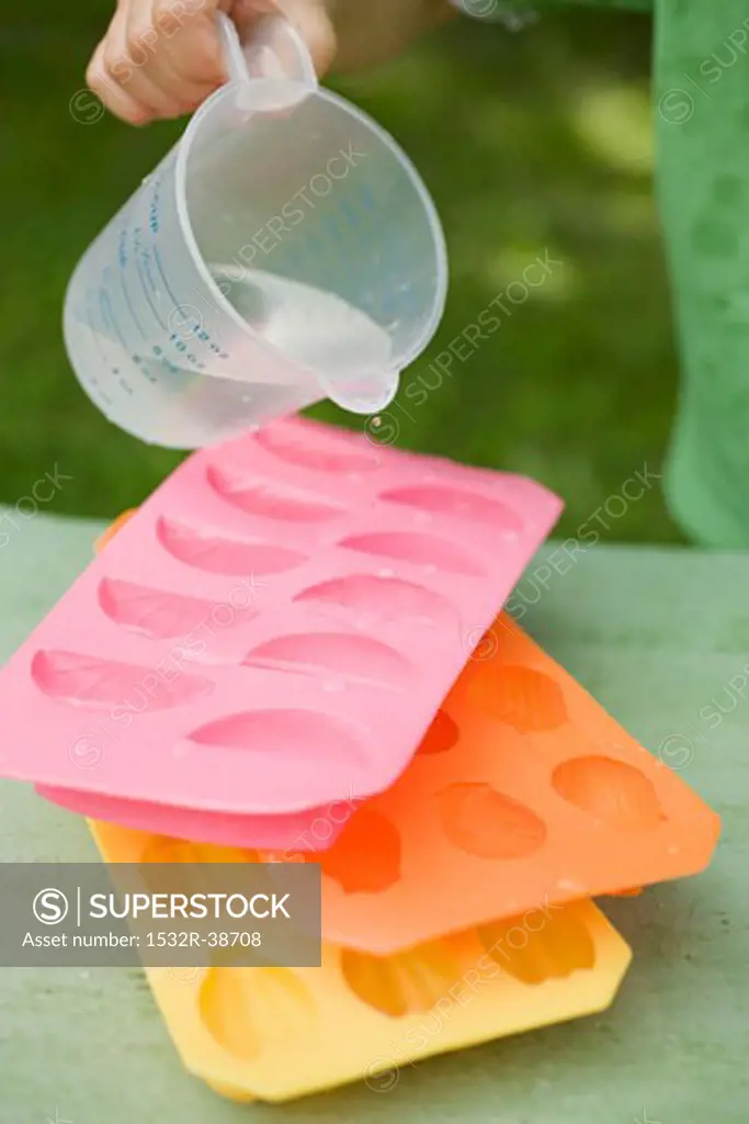 Child pouring water into ice cube tray