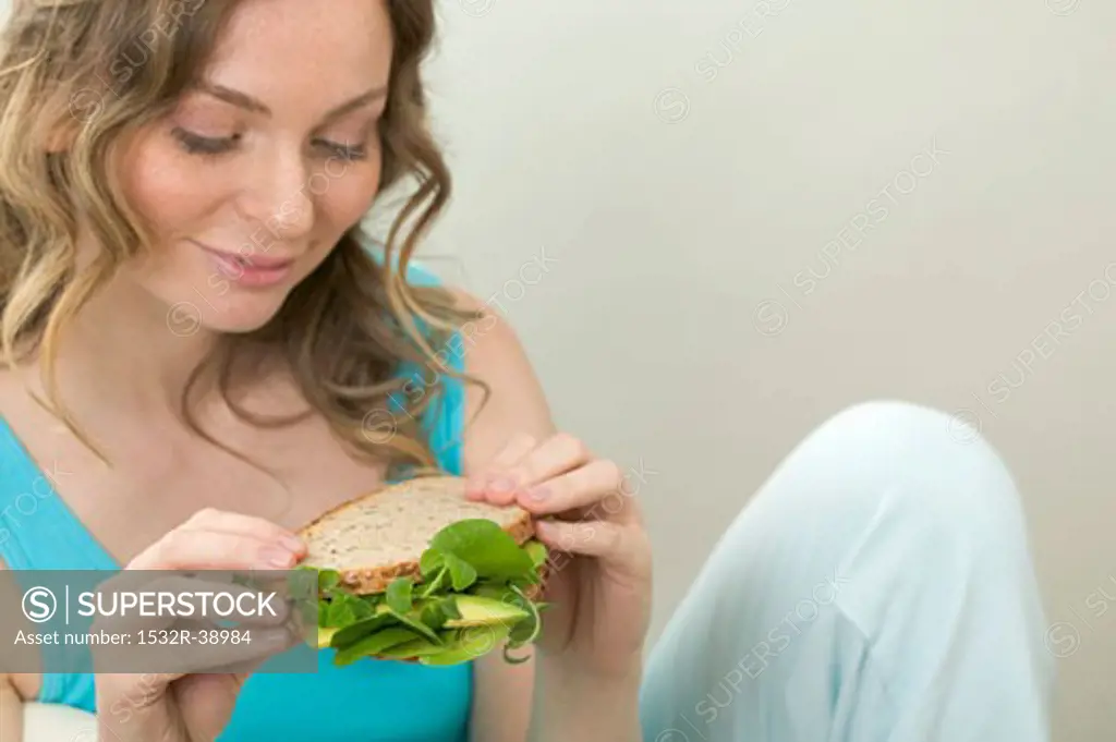 Woman holding wholemeal avocado and watercress sandwich