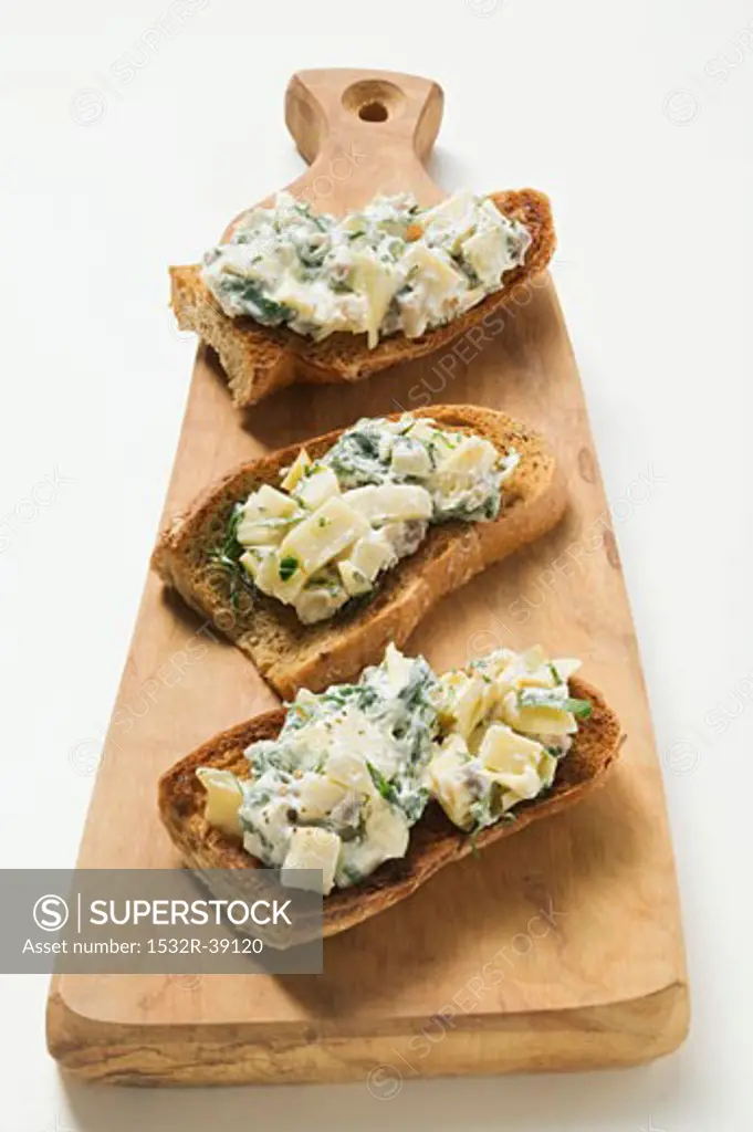 Artichokes and basil on toast on chopping board