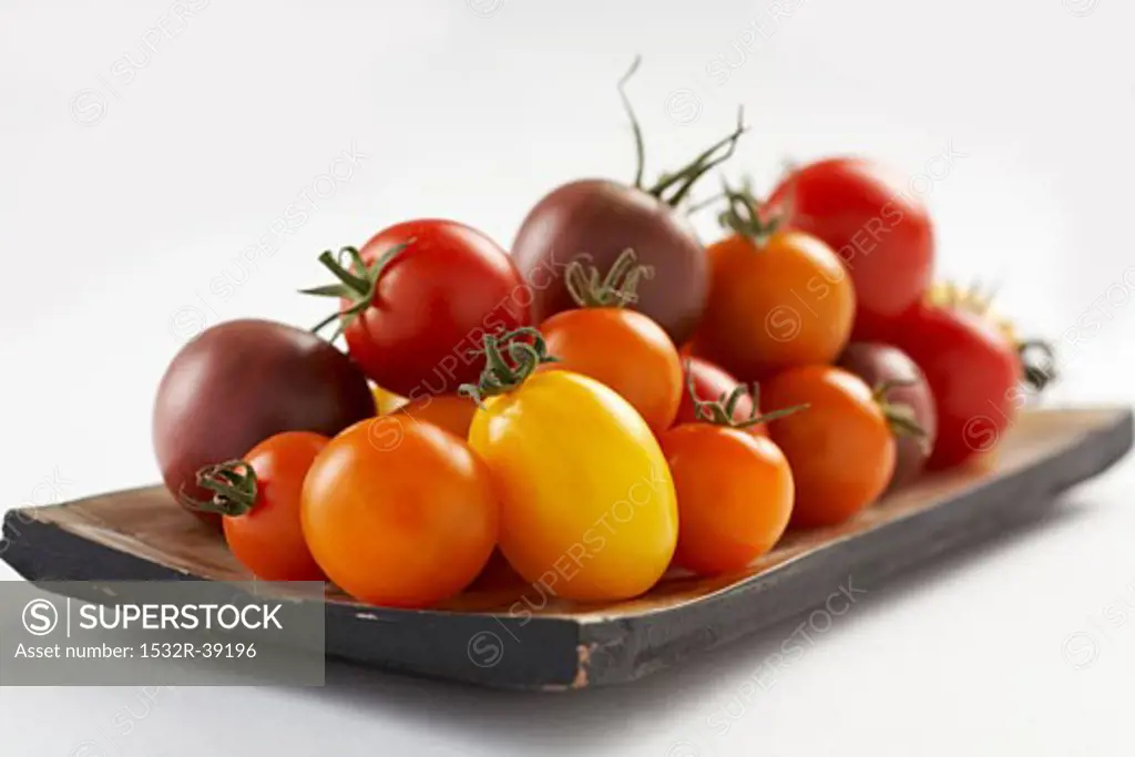 Tomatoes of various colours on wooden plate