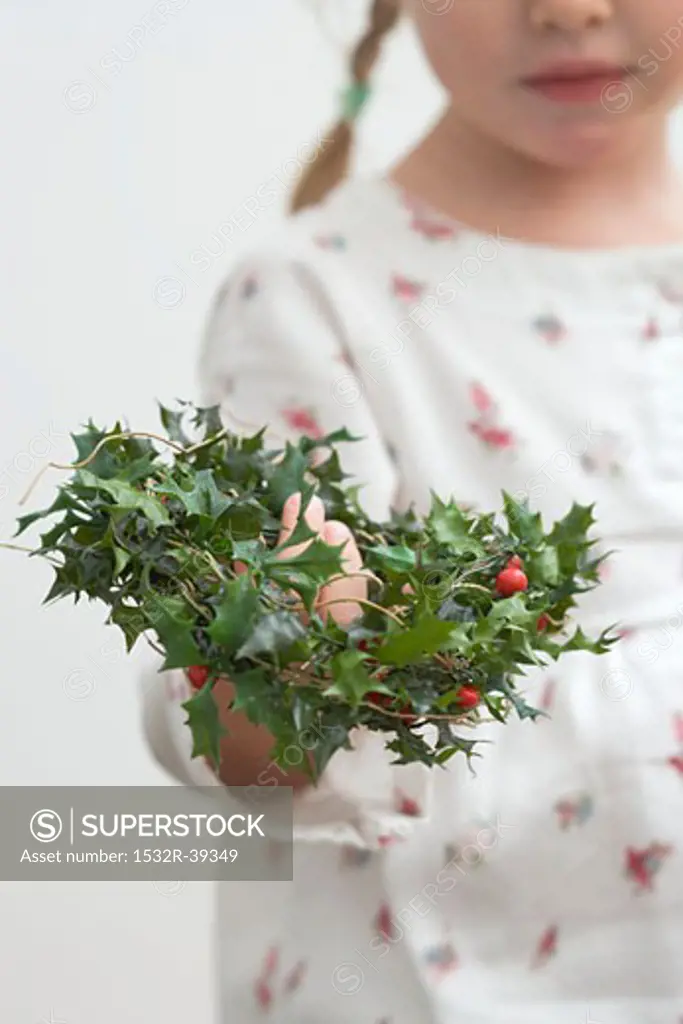 Small girl holding holly wreath