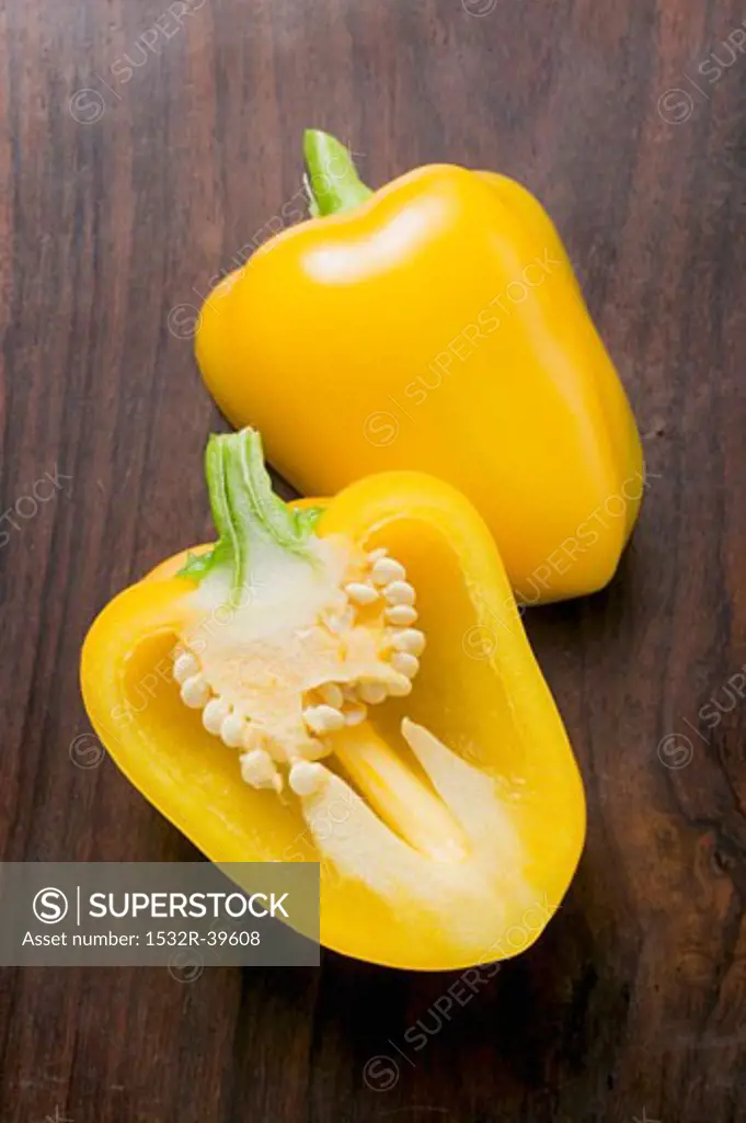 Yellow pepper, halved, on wooden background