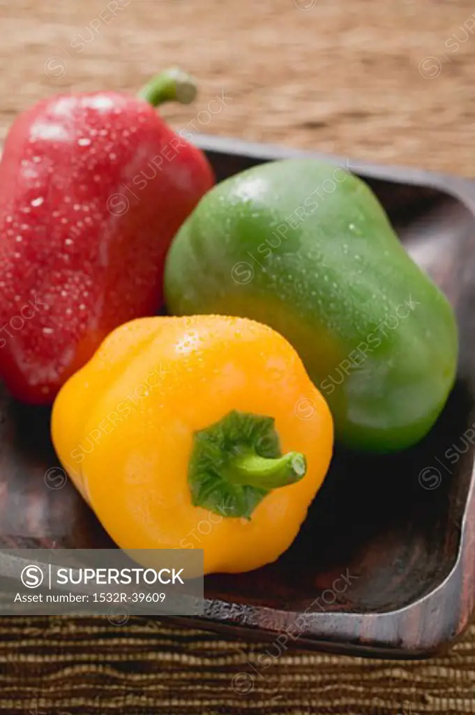 Three peppers in wooden dish