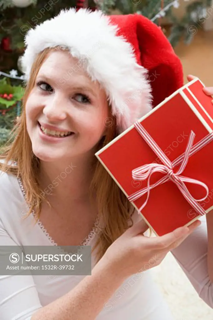 Woman in Father Christmas hat holding Christmas gift