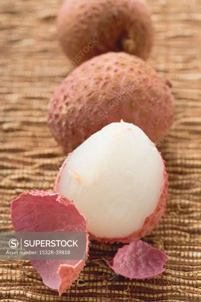 Three lychees in a row, one half-peeled