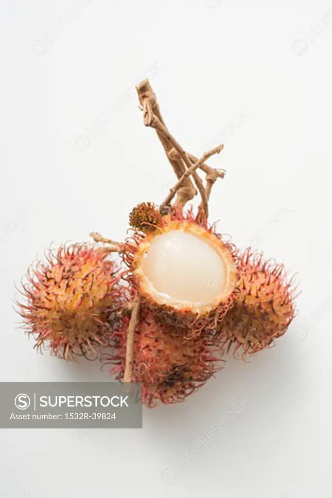 A cluster of four rambutans, one cut open