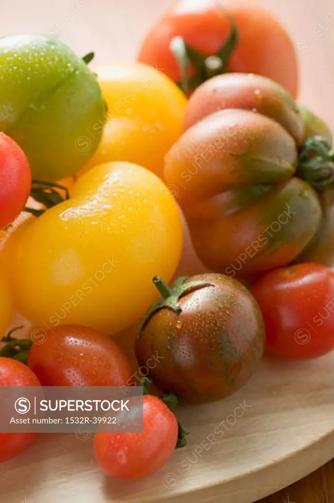 Various types of tomatoes on wooden plate (detail)
