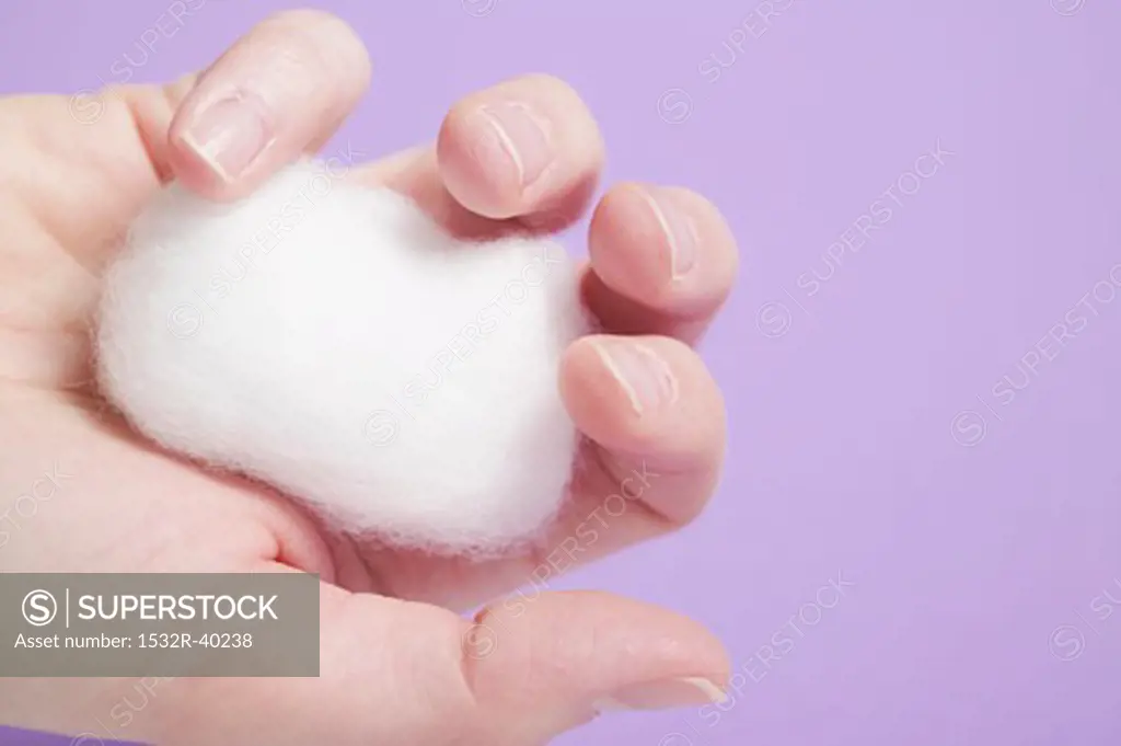 Hand holding cotton wool ball