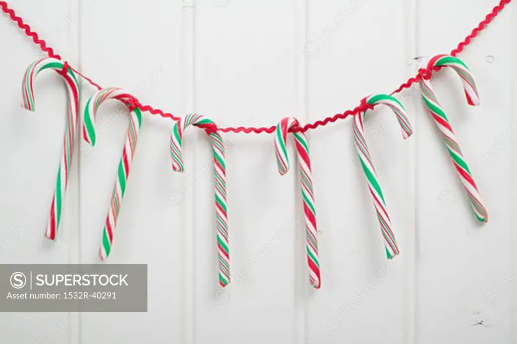 Several candy canes hanging on red ribbon