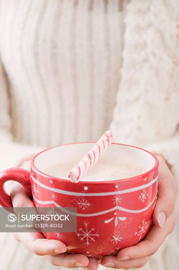 Woman holding cup of cocoa with candy cane (Christmas)