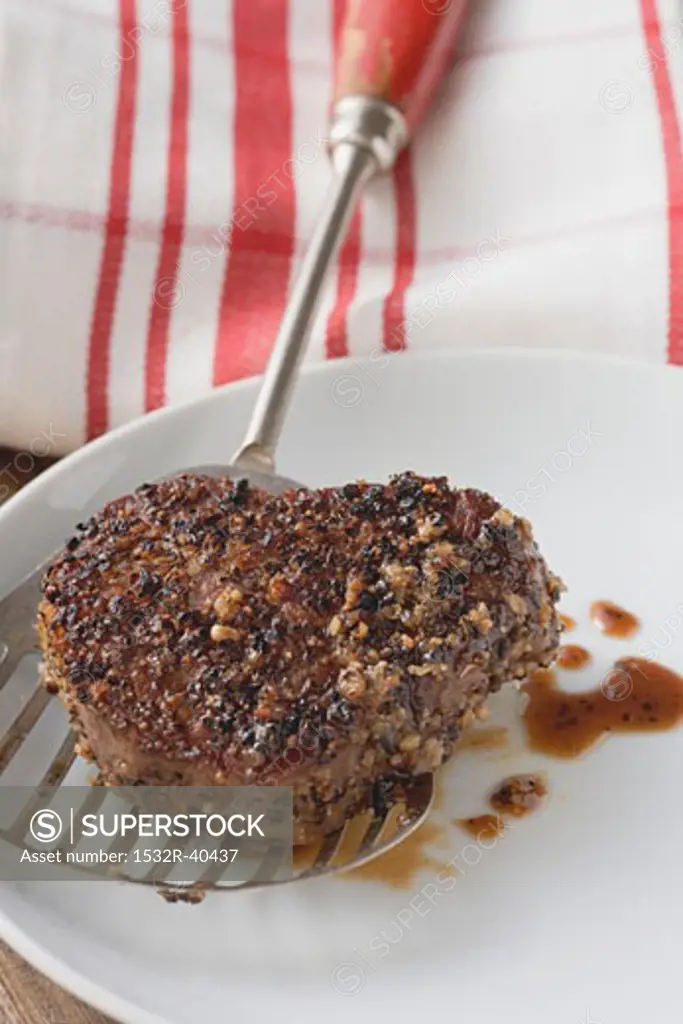 Peppered steak on spatula over plate