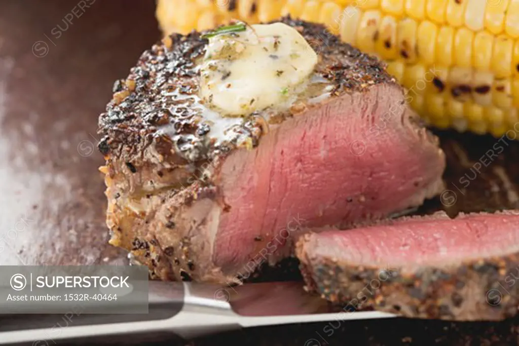 Peppered steak with herb butter and corn on the cob