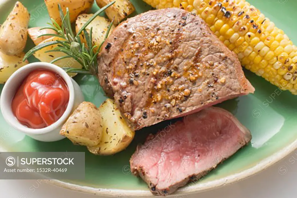 Peppered steak with corn on the cob, roast potatoes & ketchup