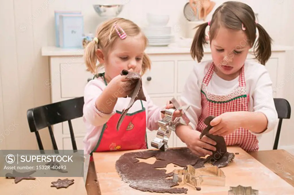 Two small girls cutting out chocolate biscuits