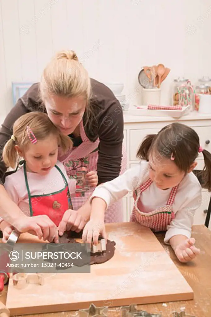 Woman and two small girls cutting out chocolate biscuits