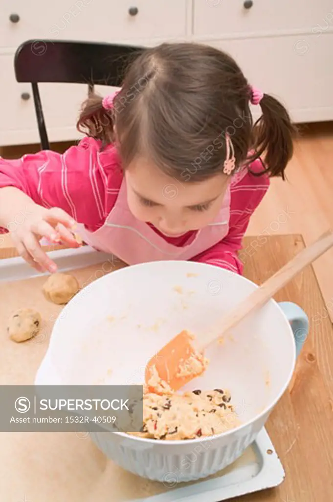 Small girl looking at mixture in mixing bowl
