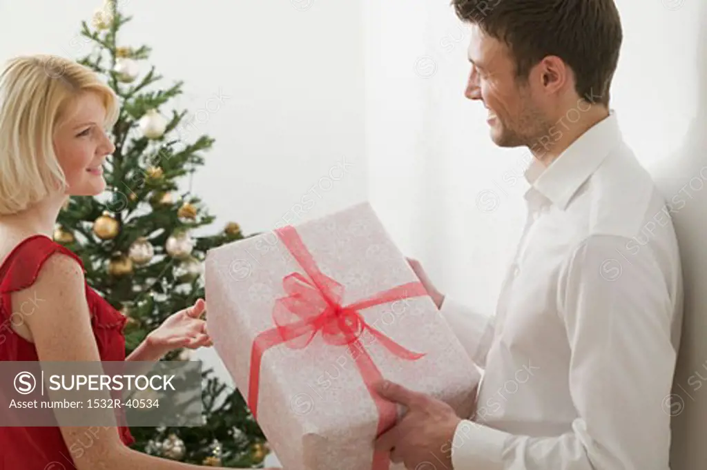 Couple with Christmas gift in front of Christmas tree