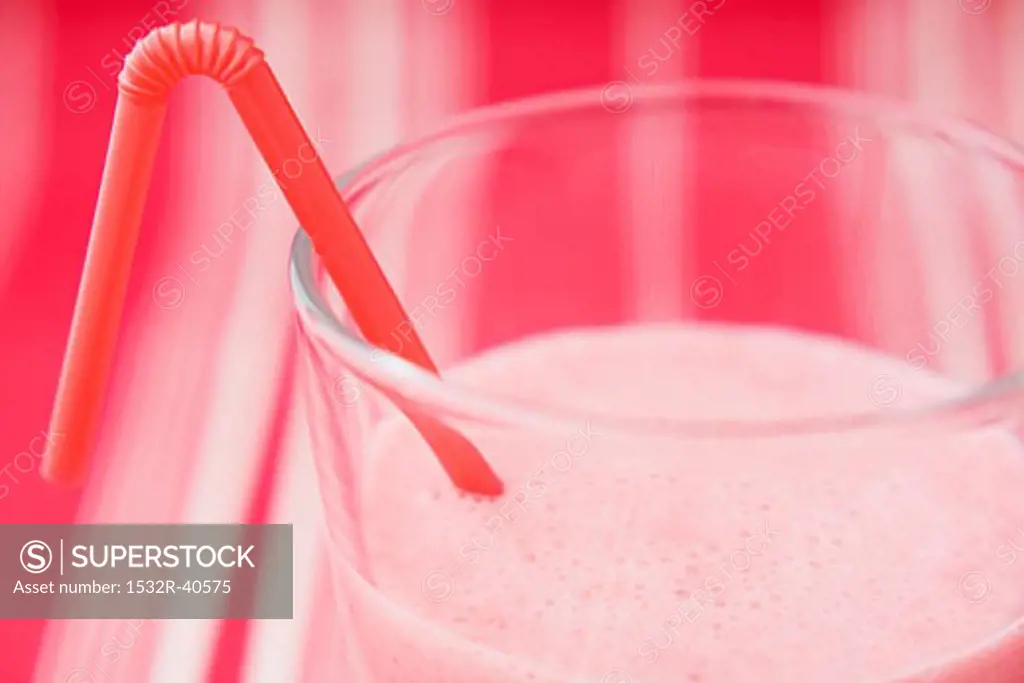 Strawberry milk in glass with straw (close-up)